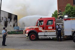 A Minneapolis police officer watches over Minneapolis firefighters who douse the aftermath of a fire following riots in May. A Minneapolis police officer watches over Minneapolis firefighters who douse the aftermath of a fire following riots in May.