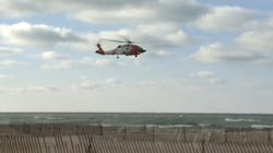 A Coast Guard helicopter flies over Lake Michigan near Muskegon, MI, after eight firefighters were swept away during a rescue attempt Sunda