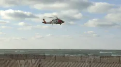 A Coast Guard helicopter flies over Lake Michigan near Muskegon, MI, after eight firefighters were swept away during a rescue attempt Sunda