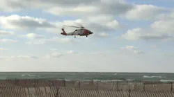 A Coast Guard helicopter flies over Lake Michigan near Muskegon, MI, after eight firefighters were swept away during a rescue attempt Sunda