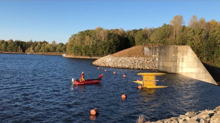A Greenville County water rescue team works to save a man from the waters of Lake Robinson near Greer, SC, as his overturned catamaran inches dangerously close to a dam and a 25-foot drop.