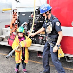 A Boise, ID, Fire Department (BFD) firefighter gives a young girl who has special needs a tour of his fire engine.