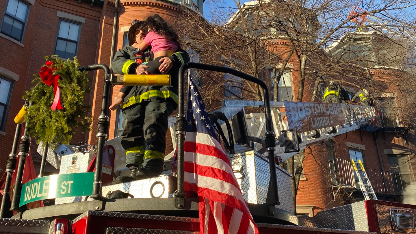 A Boston firefighter holds a girl after she was rescued from the top floor during a two-alarm residential blaze Wednesday.