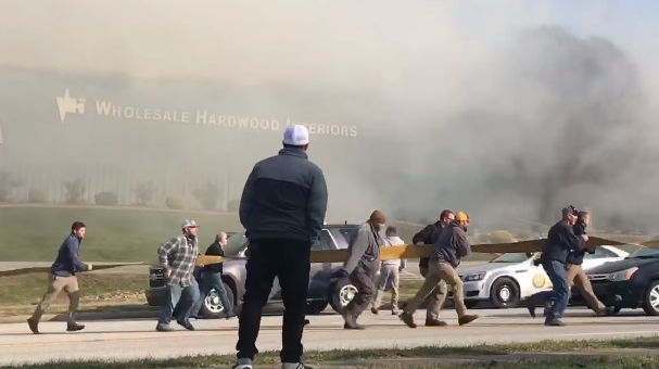 Dozens of people help pull a hoseline across a road during a massive commercial blaze in Campbellsville, KY, on Dec. 2 after a firefighter at the scene asked for help.