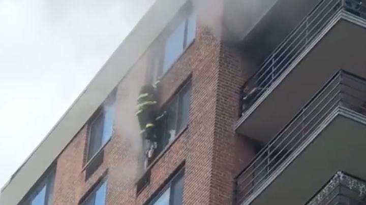 An FDNY firefighter reaches a woman on the 16th floor during a high-rise fire in Harlem on Sept. 1.