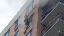 An FDNY firefighter reaches a woman on the 16th floor during a high-rise fire in Harlem on Sept. 1.