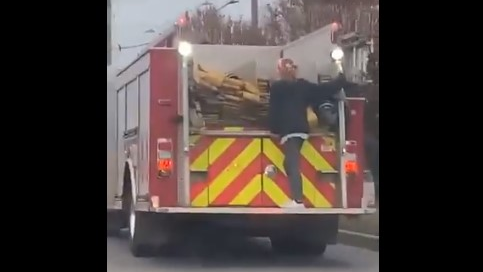 A woman is seen taking an unauthorized ride on the back of an Indianapolis Fire Department apparatus Tuesday.