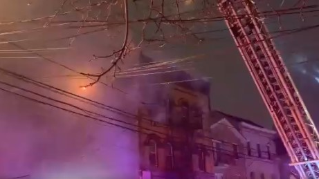 A firefighter was injured by falling debris while battling a four-alarm fire at a Passaic County, NJ, apartment building early Thursday.