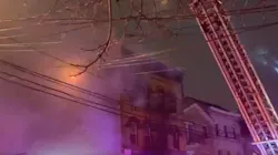 A firefighter was injured by falling debris while battling a four-alarm fire at a Passaic County, NJ, apartment building early Thursday.