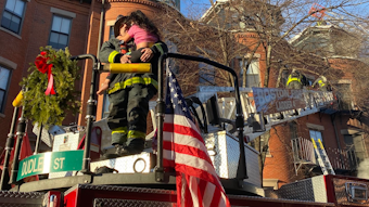 A Boston firefighter holds a girl after she was rescued from the top floor during a two-alarm residential fire in December.