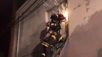 Sacramento, CA, firefighters use a power saw to cut into a vacant, boarded-up building to reach a three-alarm fire early Thursday.