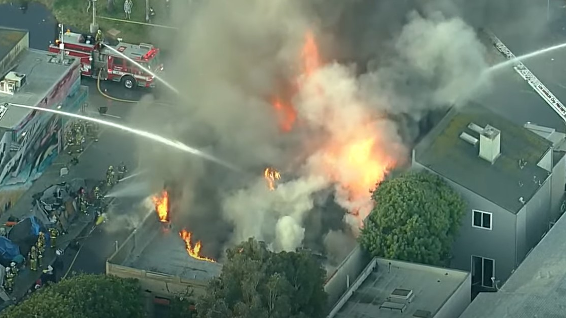 More than 100 Los Angeles City firefighters battled a massive beachfront fire that erupted at a homeless encampment near a commercial building in Venice on Wednesday.