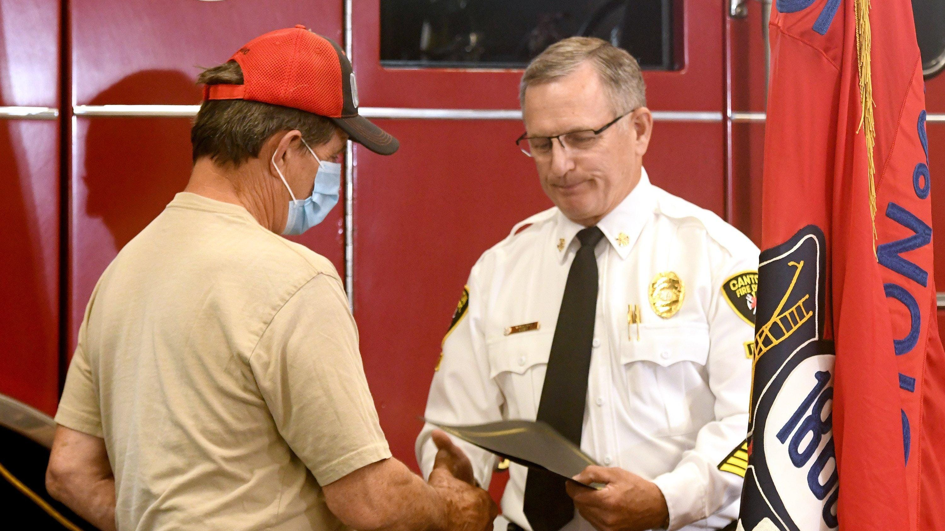 Canton, OH, Fire Chief Thomas Garra presents a Good Samaritan award to Norman Yoder, who used his ladder to help four people flee a burning house.