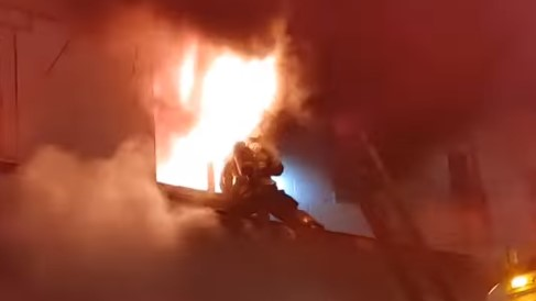 A Baltimore City firefighter avoids flames as they shoot out of a second-story window of a burning rowhouse Friday.