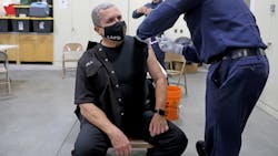 Los Angeles Fire Department fire inspector John Novela (left) receives a Moderna COVID-19 vaccination given by Mario Guillen, a firefighter paramedic, at Station 4 on Dec. 28. Los Angeles Fire Department fire inspector John Novela (left) receives a Moderna COVID-19 vaccination given by Mario Guillen, a firefighter paramedic, at Station 4 on Dec. 28.