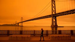 A woman walks along The Embarcadero under an orange smoke-filled sky in San Francisco on Sept. 9.