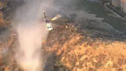 Los Angeles County firefighters battled a brush that erupted following an explosion at a Santa Clarita industrial park that critically injured three people Tuesday.
