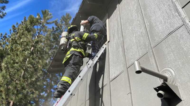 A South Lake Tahoe, CA, firefighter rescues a resident from the second floor of a burning apartment building Monday.