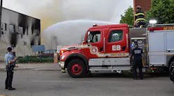 A Minneapolis police officer watches over firefighters who douse the aftermath of a fire following riots in May.