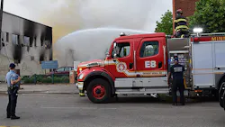 A Minneapolis police officer watches over firefighters who douse the aftermath of a fire following riots in May.