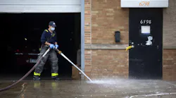 A Chicago firefighter cleans up blood as Chicago police officers work the scene of a mass shooting Sunday morning.