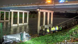 Firefighters stand by as the truck is pulled from the Trinity River early Sunday.