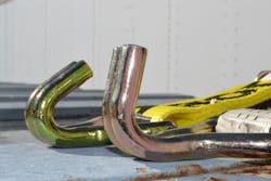 Premise 3. The standard twin hooks (background) show their normal curved shape. When the peak load exceeded 12,000 lbs., the hooks were overloaded and began to bend and straighten as shown (foreground). In some destructive tests, the metal fractured when overloaded.