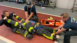Firefighters in their turnout gear train on extricating a firefighter who is in cardiac arrest. Firefighters in their turnout gear train on extricating a firefighter who is in cardiac arrest.