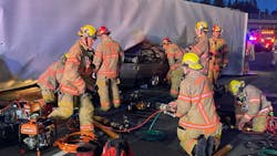 Portland, OR, firefighters extricated two people from a car that was pinned under an overturned tractor-trailer early Wednesday. Portland, OR, firefighters extricated two people from a car that was pinned under an overturned tractor-trailer early Wednesday.