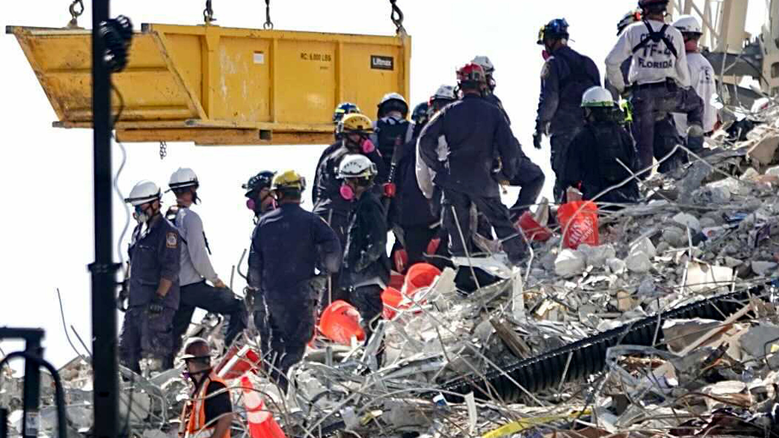 A bucket brigade works to remove debris from the Champlain Towers South Condo collapse Monday in Surfside, FL.