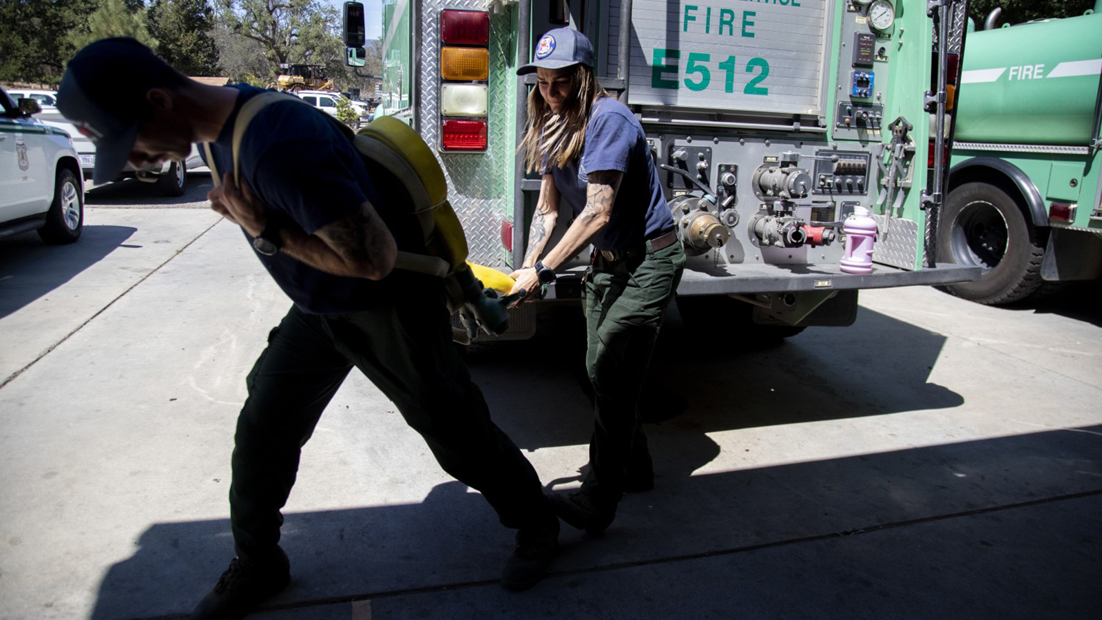U.S. Forest Service firefighters Nick Browne (left) and Justine Gude deploy a Gasner hose pack during a training demonstration at the Oak Flat Fire Station on July 3 in Castaic, CA. The hose packs are fire hoses folded in a unique way enabling firefighters to carry the pack on their backs and deploy them in fighting wildfires.