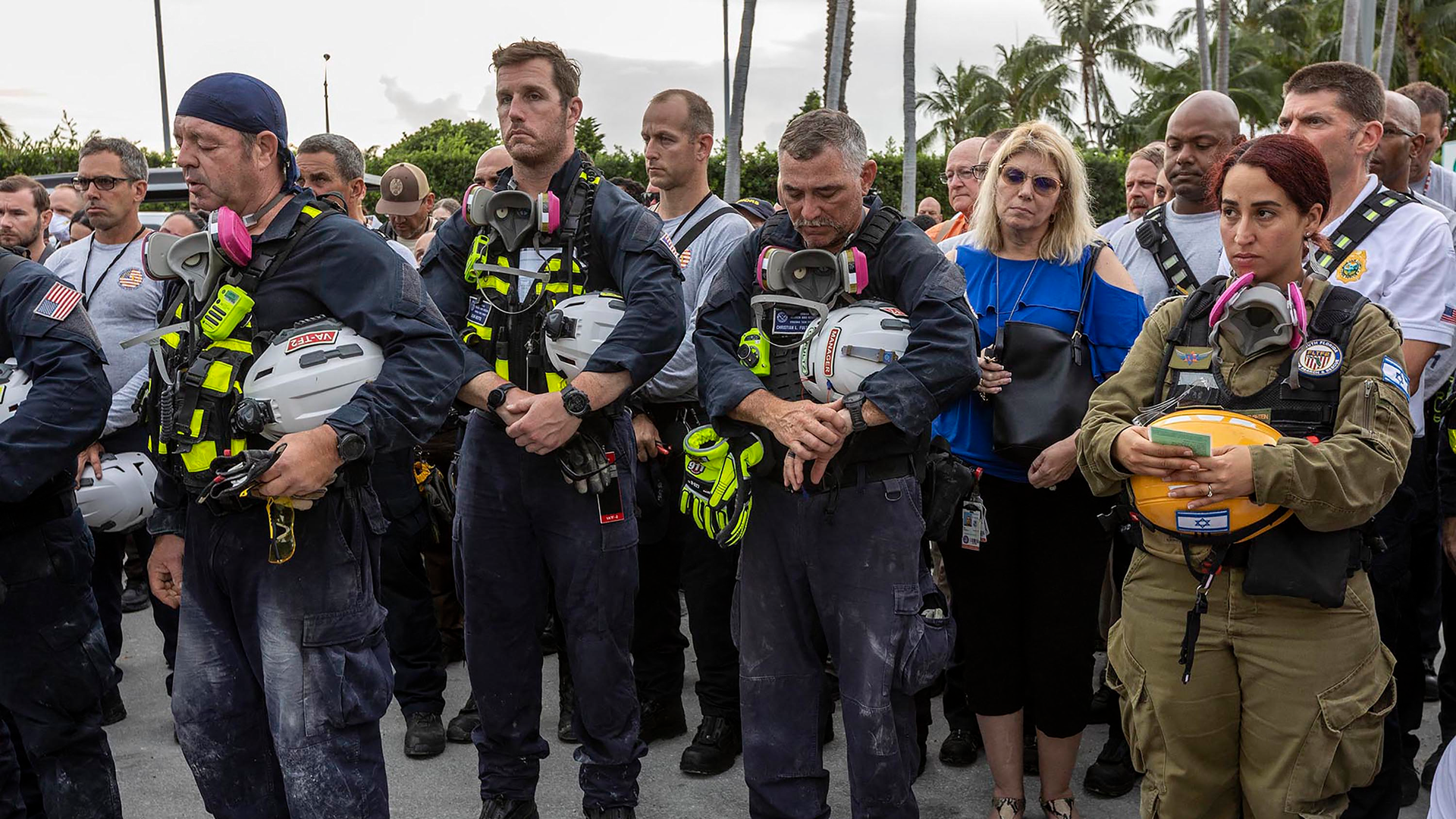 Miami-Dade County officials, members of Miami-Dade Search and Rescue and Miami-Dade Fire Rescue, as well as police officers gather for a moment of prayer and silence in front of the rubble of the collapsed tower in Surfside, FL, on Wednesday.
