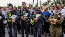 Miami-Dade County officials, members of Miami-Dade Search and Rescue and Miami-Dade Fire Rescue, as well as police officers gather for a moment of prayer and silence in front of the rubble of the collapsed tower in Surfside, FL, on Wednesday.