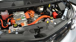 A 1st Responder Cut Label (yellow) for this Chevrolet Bolt EV is visible at upper right along the firewall. The larger label at lower left on the top of the radiator trim piece indicates that there is a 400-volt lithium-ion battery onboard and that the 12-volt battery is in this front compartment, somewhat buried on the lower left side. A 1st Responder Cut Label (yellow) for this Chevrolet Bolt EV is visible at upper right along the firewall. The larger label at lower left on the top of the radiator trim piece indicates that there is a 400-volt lithium-ion battery onboard and that the 12-volt battery is in this front compartment, somewhat buried on the lower left side.