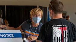 Amy Kotsopoulos with DetecTogether directs a firefighter arriving for free skin cancer screenings at Polar Park in Worcester, MA, on Tuesday, Aug. 24, 2021.