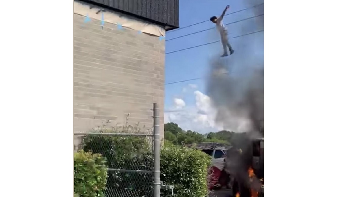 A man trapped on burning a lift 25 feet jumps onto a makeshift net during a rescue by Oxford, AL, firefighters on Saturday.