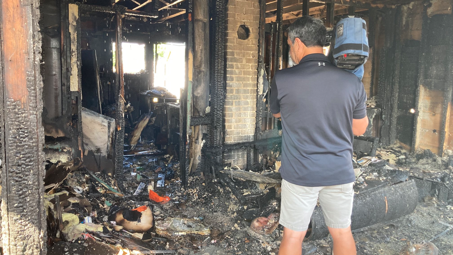 A news cameraman stands inside a home destroyed in a fire that also claimed three lives in Spokane, WA, on Sunday, Aug. 22, 2021.