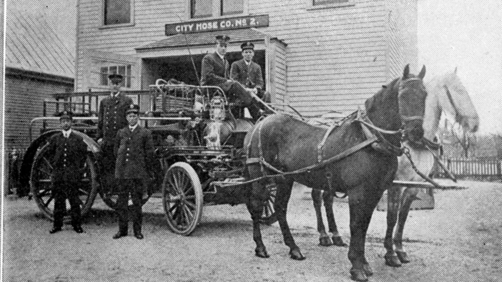 The Lexington Hose and Chemical Company Station #2 is pictured in the background of this 1898 photo of firefighters and a horse-drawn fire apparatus.