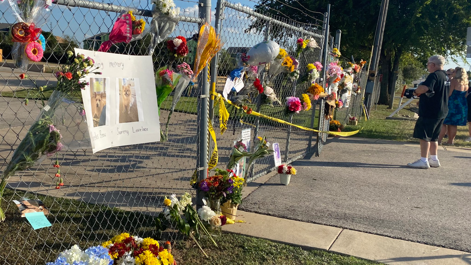 Flowers and photos hang on a gate outside the Ponderosa Pet Resort in Georgetown, TX, after 75 dogs being boarded there perished in a fire on Saturday, Sept. 18, 2021.
