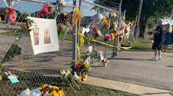 Flowers and photos hang on a gate outside the Ponderosa Pet Resort in Georgetown, TX, after 75 dogs being boarded there perished in a fire on Saturday, Sept. 18, 2021.