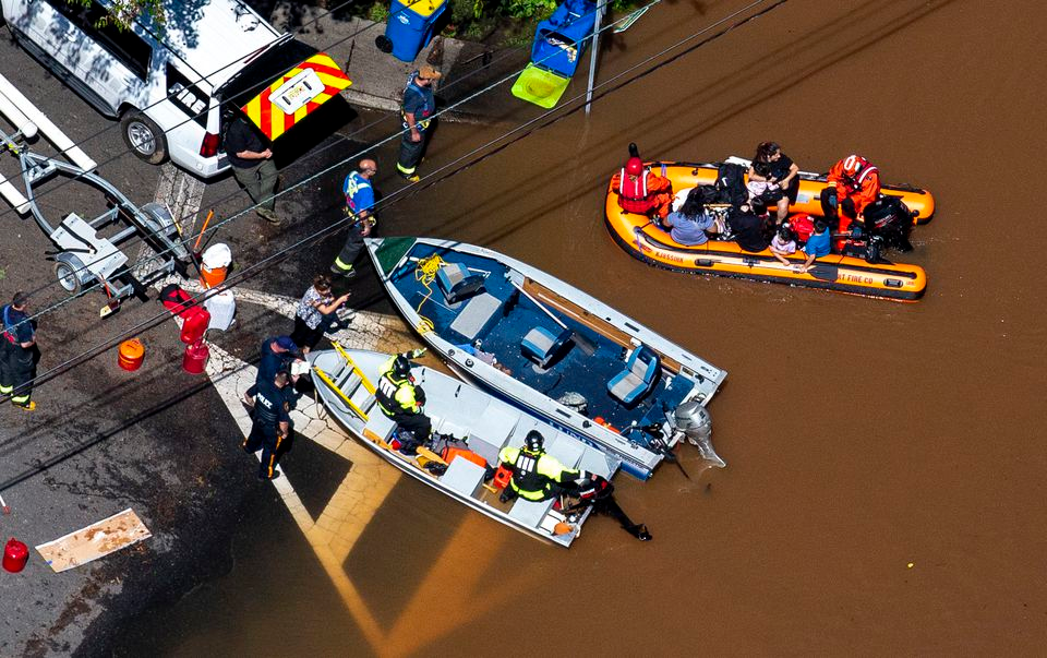 Emergency personnel use a boat to rescue people stranded in a flooded section of Manville Thursday.