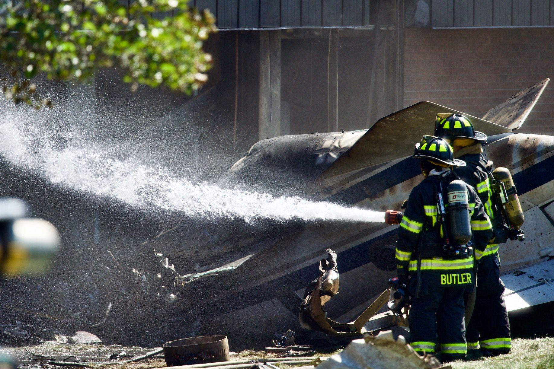 Firefighters wet down the area where a small plane crashed into a manufacturing building Thursday.