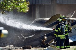 Firefighters wet down the area where a small plane crashed into a manufacturing building Thursday. Firefighters wet down the area where a small plane crashed into a manufacturing building Thursday.