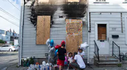 Neighbors pay their respects outside a boarded-up home where a man and his 14-year-old nephew perished in a fire in Allentown, PA, in July 2020.