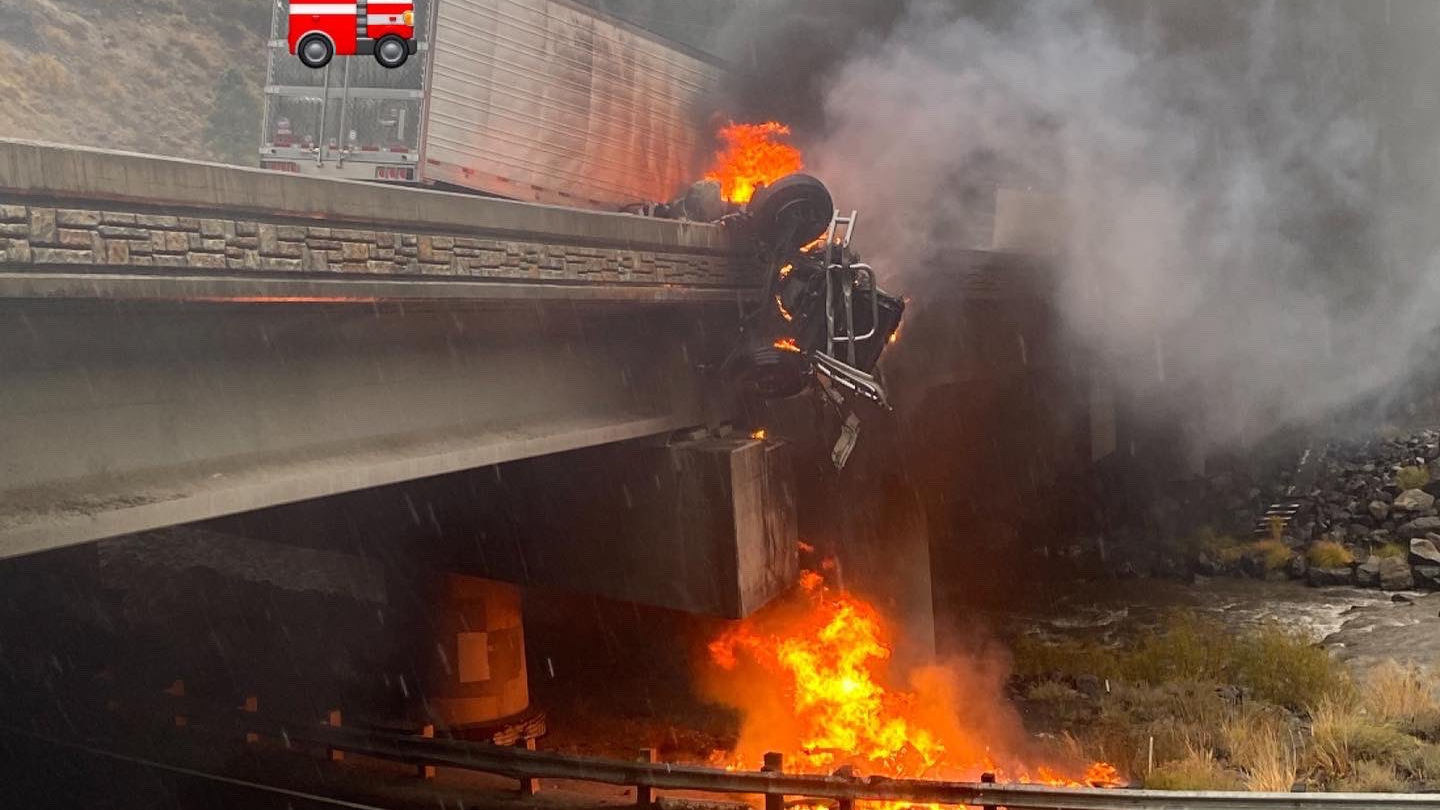 A burning semi truck hangs off the side of a bridge in Floriston, CA, after a crash on Sunday, Oct. 24, 2021.
