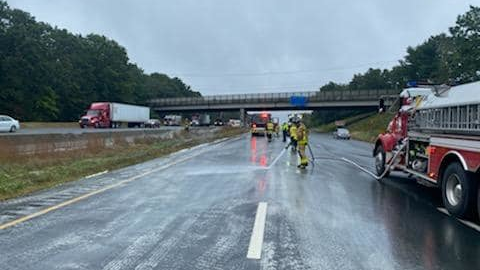 A Tolland firefighter hoses down I-84 after a semi-trailer hauling gypsum powder struck an overpass on Oct. 4, 2021.