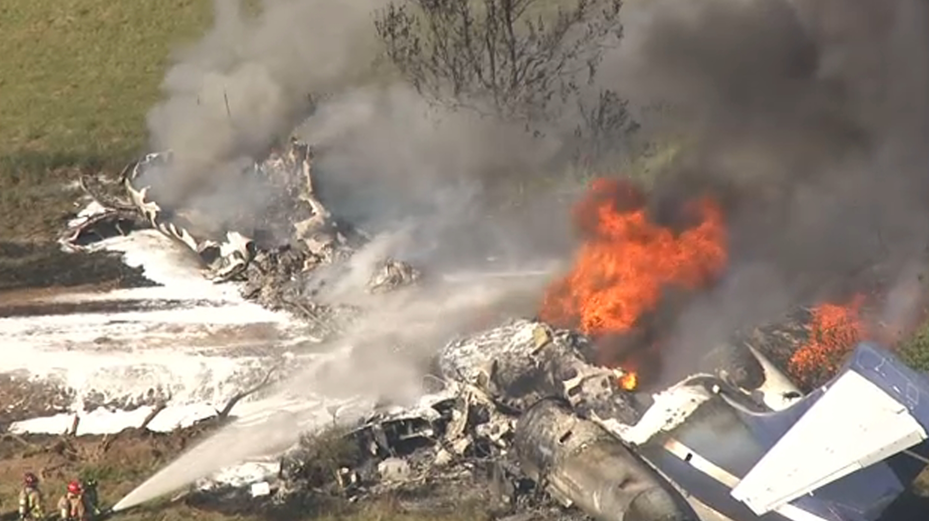 Firefighters douse a burning plane with foam following a crash near Houston Executive Airport on Tuesday, Oct. 19, 2021.