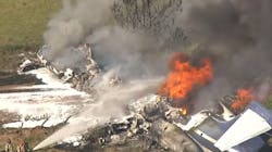 Firefighters douse a burning plane with foam following a crash near Houston Executive Airport on Tuesday, Oct. 19, 2021.