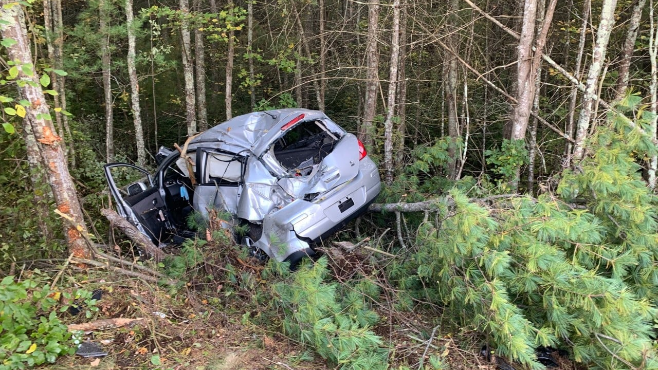 A mangled vehicle sits in a wooded area along Route 140 in Lakeville, MA, after a crash that ejected and badly injured the driver.