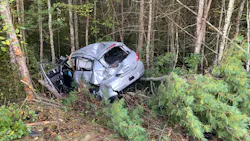 A mangled vehicle sits in a wooded area along Route 140 in Lakeville, MA, after a crash that ejected and badly injured the driver.